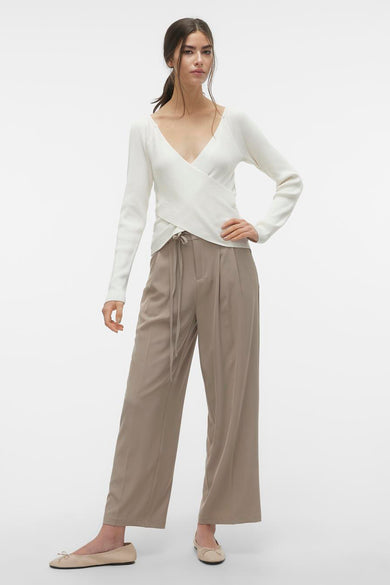 Beige broek van VERO MODA, met wijde pijpen en een striksluiting, gecombineerd met een witte wikkel top en beige ballerina's.
