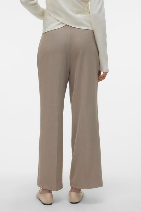 Beige broek van VERO MODA, gezien van achteren, gecombineerd met een crèmekleurige trui en platte schoenen.