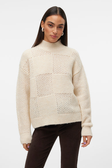 T-shirt à col montant écru de VERO MODA, avec motif patchwork et porté avec un pantalon en corduroy marron.