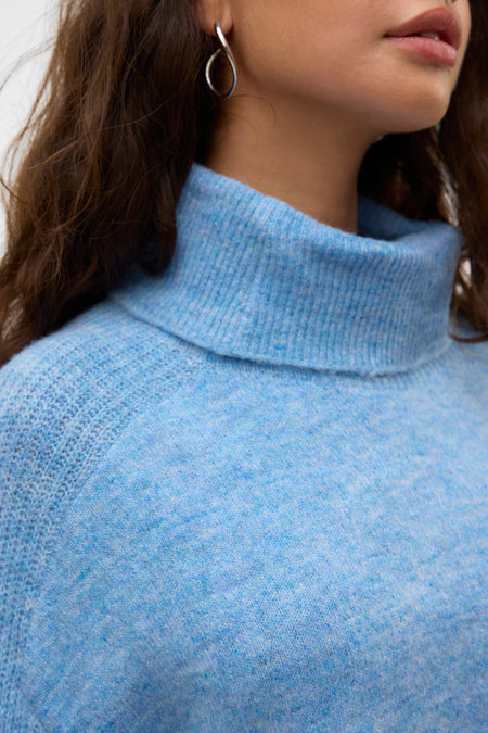 Jean bleu col montant de VERO MODA, avec une douce texture et porté avec des boucles d'oreilles en argent.