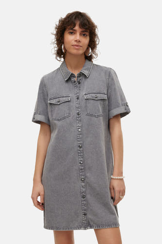 Femme en jupe denim gris avec des boutons et des bottes brunes.