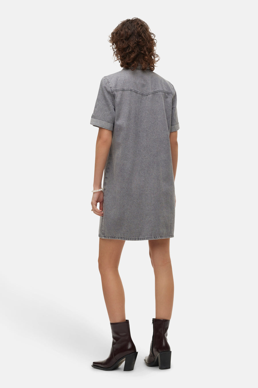 Vêtement gris à manches courtes de VERO MODA, vu de dos, avec des bottes brunes et un bracelet de perles.