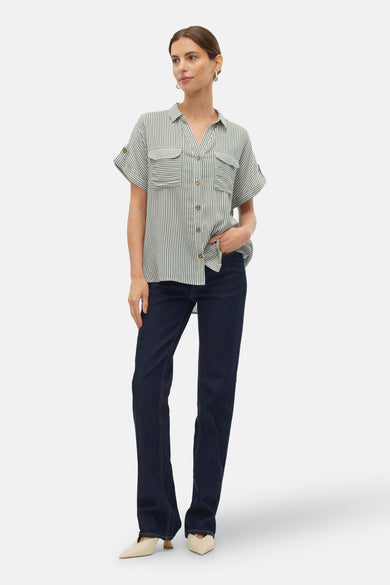 Chemise rayée verte de VERO MODA, à manches courtes, avec col boutonné et poches brodées, portée avec des jeans foncés et des baskets.