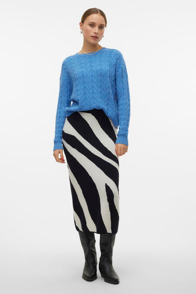 Lange zwarte rok van VERO MODA® met een zebraprint en gecombineerd met zwarte laarzen en een blauwe trui.
