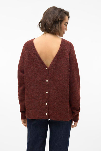 Donkerroodbruine trui met V-hals en knoopsluiting op de rug, gecombineerd met donkere jeans.