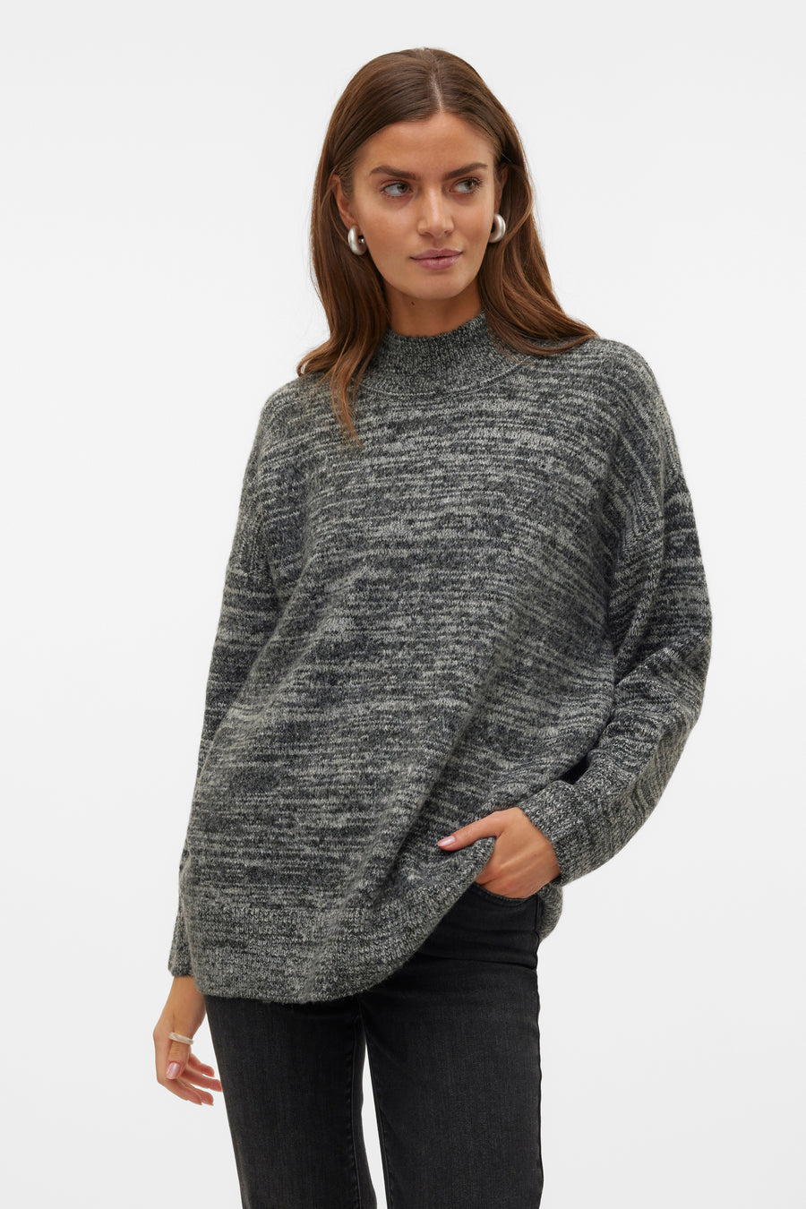 Vrouw in grijze, gebreide trui met col en zwarte jeans.