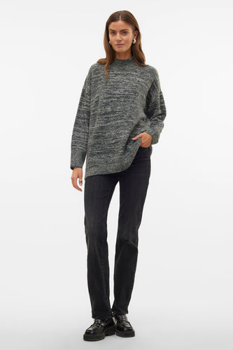 Vrouw in grijze trui en zwarte jeans.