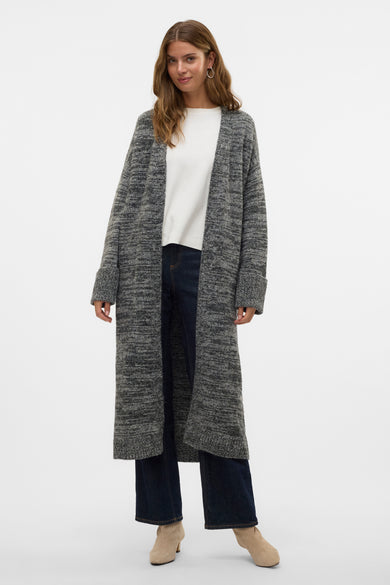Gilet noir de Vero Moda, vu de de derrière, avec une longue coupe sur un jeans foncé et des bottes beige.