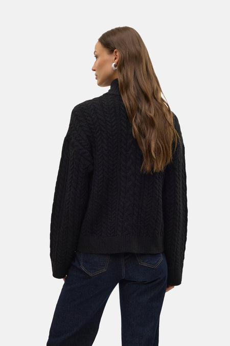 Veste noire de VERO MODA, avec un motif côtelé, portée sur un pantalon en cuir noir.