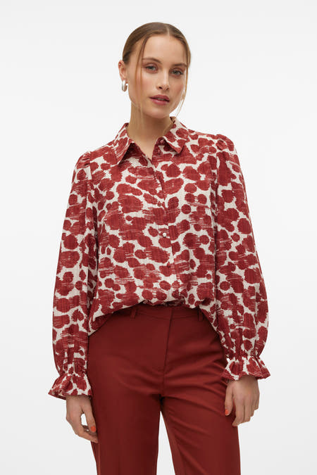Chemise brune à manches longues de VERO MODA, avec imprimé fleurs rouges et blanches, associée à une jupe rouge.