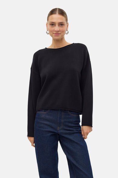 Pull noir avec col rond de VERO MODA, associé à un jean foncé et des boucles d'oreilles argentées.