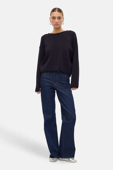 Pull noir avec col rond de VERO MODA, associé à des jeans bleu marine et des chaussures argentées.