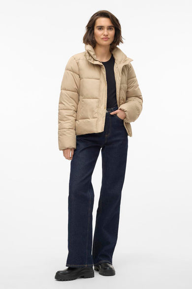 Beige korte jas van VERO MODA, met opstaande kraag en gedragen met donkere jeans en zwarte laarzen.