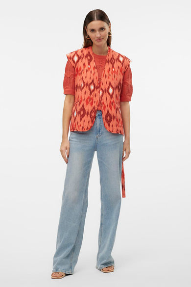 Oranje bodywarmer van VERO MODA met ikat-patroon, gecombineerd met een oranje top en wijde jeans.