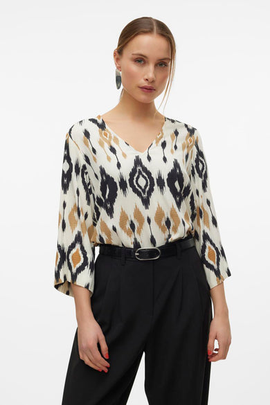 Blouse multicolore à manches trois-quarts de Vero Moda, avec un motif ikat et associée à un pantalon noir et une ceinture.
