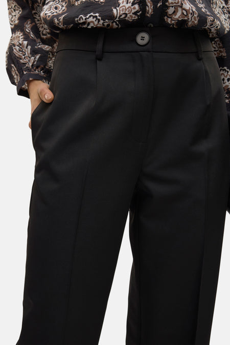 Pantalon noir de VERO MODA®, avec une fermeture à boutons et une main dans la poche.