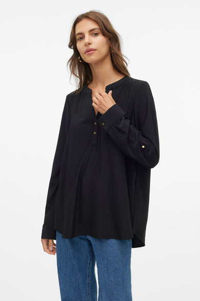 Blouse noire à longues manches de VERO MODA, avec des boutons dorés et portée avec un jean bleu.