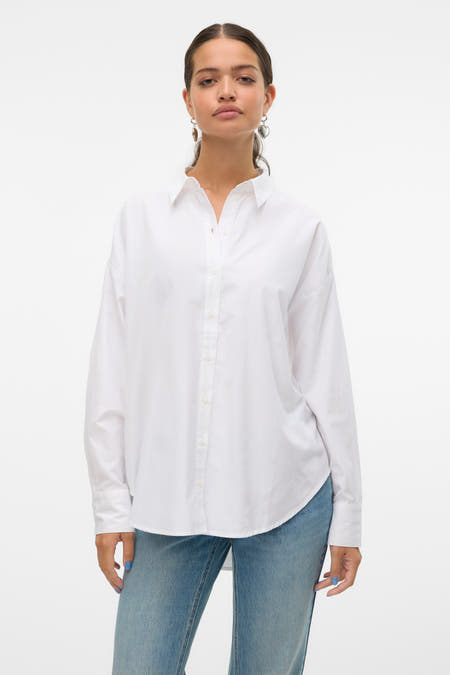 Blouse blanche à manches longues de VERO MODA, vue de dos, avec des jeans bleus et des boucles d'oreilles argentées.