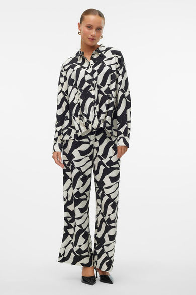 Veelkleurig overhemd met lange mouwen van VERO MODA, met een opvallend zwart-wit golvend patroon, gedragen met bijpassende broek en zwarte pumps.