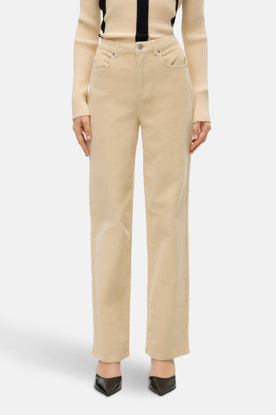 Jean écru de VERO MODA®, réalisé en tricot et associé à une chemise beige et des escarpins noirs.