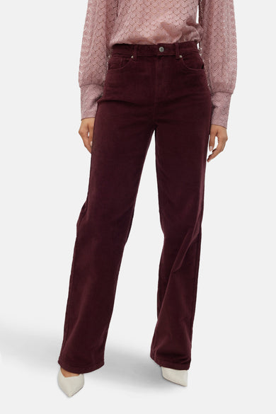 Pantalon Bordeaux de VERO MODA, avec des jambes larges et fabriqué en corduroy, associé à une blouse rose à imprimé fleuri.