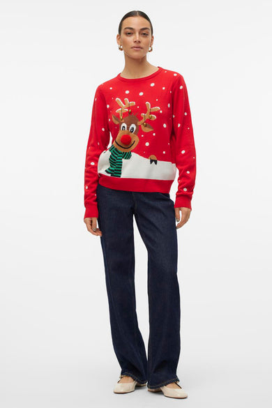 Pull-over rouge avec col rond de VERO MODA, imprimé de rennes et de flocons de neige.Porté avec des jeans bleu marine et des chaussures crème.