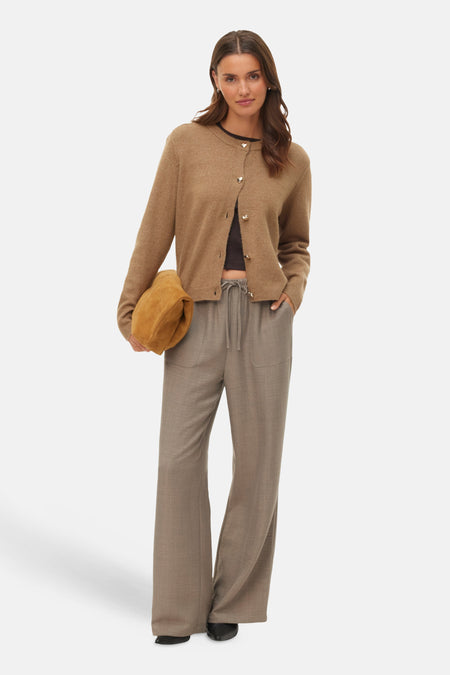 Model draagt bruin vest en wijde broek.