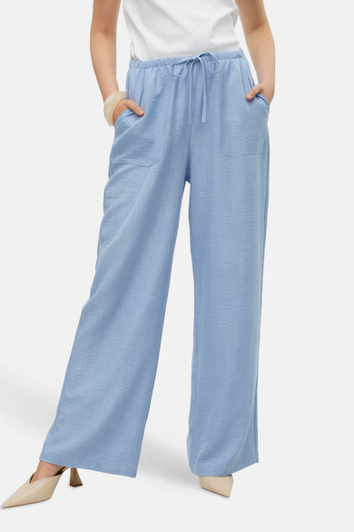 Jean bleu de VERO MODA, associé à un T-shirt blanc, une chaîne en or et des chaussures beige.