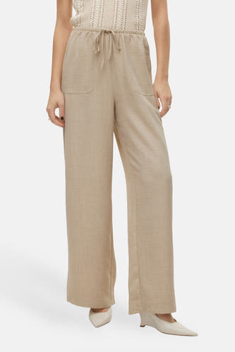 Jean beige de VERO MODA, avec cordon et poches, porté avec des chaussures blanches.