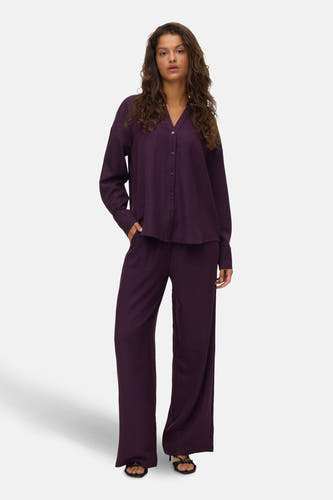 Rose, chemise à longues manches de VERO MODA®, portée avec un pantalon coordonné et des sandales noires.