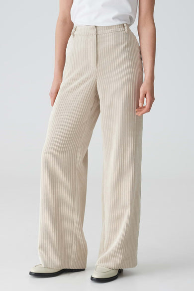 Pantalon en velours côtelé beige d'OPUS à jambes larges, stylisé avec un t-shirt blanc et des mocassins de couleur crème.