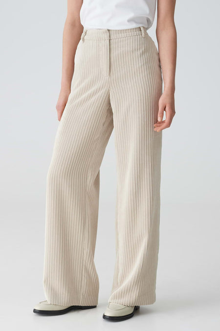 Pantalon en velours côtelé beige d'OPUS à jambes larges, stylisé avec un t-shirt blanc et des mocassins de couleur crème.
