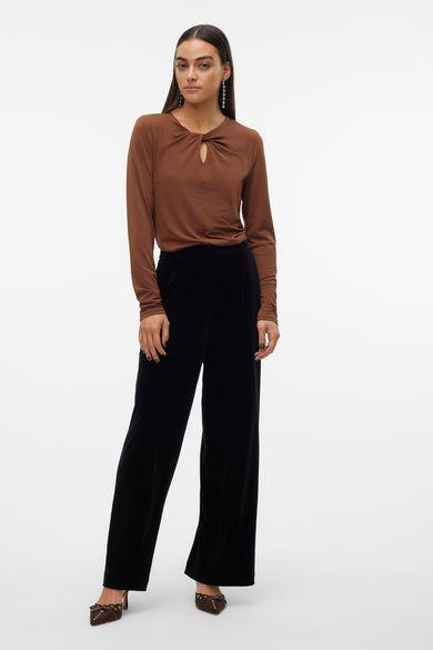 Blouse brune à longues manches de VERO MODA, avec détail d'œil de verrou à l'avant et portée avec un pantalon noir et des boucles d'oreilles.
