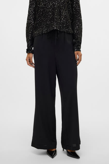 Pantalon noir de VERO MODA, associé à une chemise scintillante, avec des jambes larges et une ceinture élastiquée.