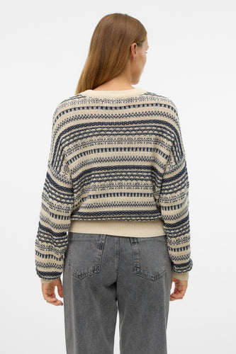 Achterkant van een vrouw in een gestreepte trui en grijze jeans.
