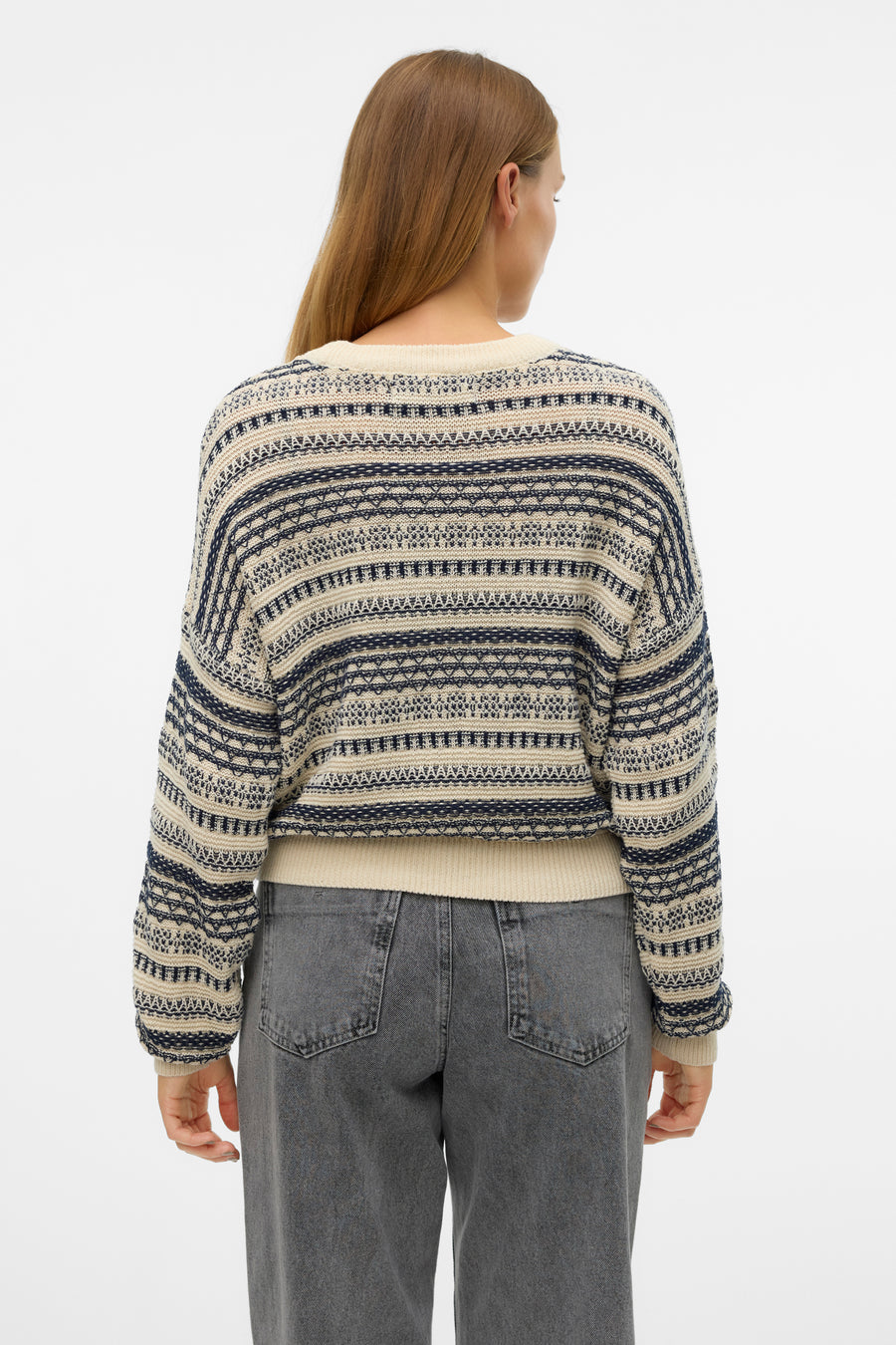 Achterkant van een vrouw in een gestreepte trui en grijze jeans.
