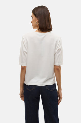 Pull blanc à col rond de VERO MODA®, vu de dos, associé à un jean bleu foncé et des boucles d'oreilles dorées.