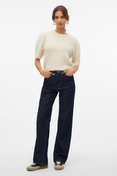 T-shirt écru avec col rond de Vero Moda, manches courtes, associé à des jeans foncés et des baskets basses.