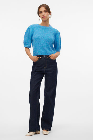 Pull rond bleu de VERO MODA®, avec des manches bouffantes, associé à des jeans foncés et des chaussures crème.