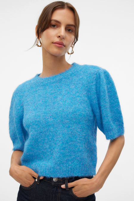 T-shirt bleu avec col rond de VERO MODA, à manches courtes, porté avec un jeans foncé et des boucles d'oreilles dorées.