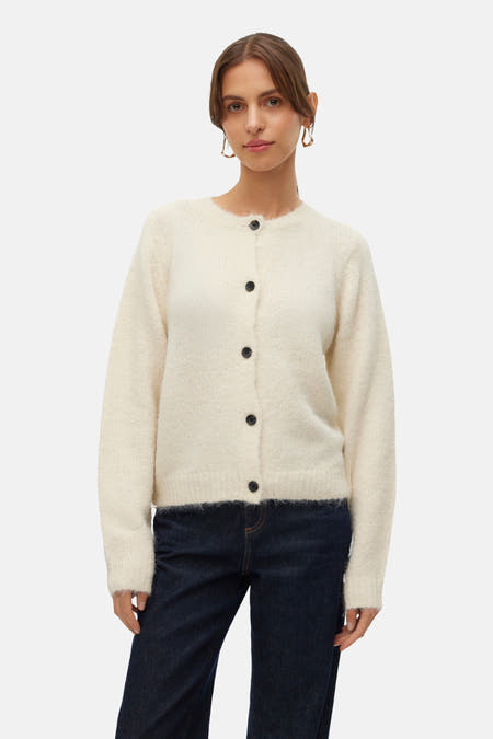 Veste écru de VERO MODA®, à longues manches, boutons noirs et portée avec un jeans foncé.