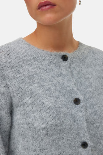 Cardigan gris de VERO MODA, avec fermeture à boutons et une douce texture, porté avec des boucles d'oreilles argentées.