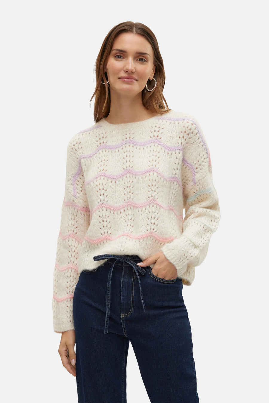 Ecrukleurige trui met ronde hals van VERO MODA, met pastelkleurige golvende strepen en opengewerkt breisel, gedragen met een donkerblauwe jeans.
