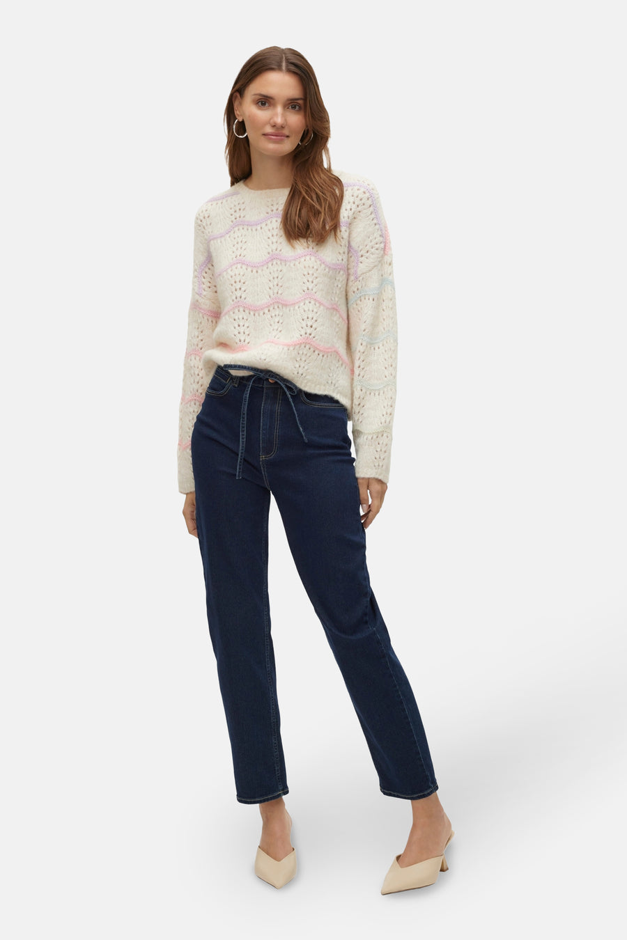 Ecru trui met ronde hals van Vero Moda, met pastelkleurige zigzagstrepen, gecombineerd met donkerblauwe jeans en beige muiltjes.
