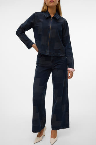 Jean large bleu marine denim de VERO MODA, avec un motif patchwork et associé à des sandales légères et un bracelet rose.