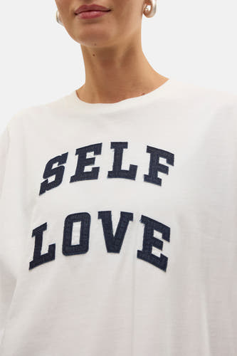 T-shirt blanc à manches courtes de Vero Moda, avec le texte "Self Love" dans un look denim.
