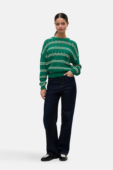 T-shirt vert avec col rond de VERO MODA, avec un motif à rayures ondulées décoratives et des jeans foncés.