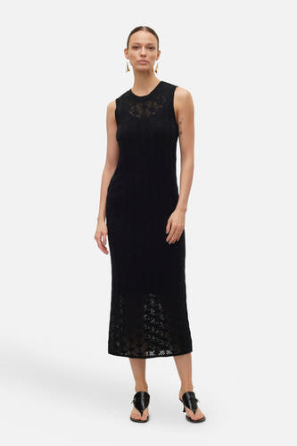 Robe sans manches noire de VERO MODA, avec un motif décoratif et associée à des sandales noires.