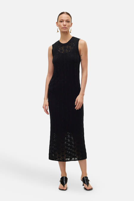 Robe sans manches noire de VERO MODA, avec un motif décoratif et associée à des sandales noires.
