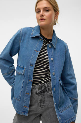 Jean en medium bleu denim de VERO MODA, avec des poches cousues et une chemise rayée dessous.